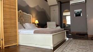 Una camera da letto con un letto, una sedia, una lampada, un armadio e un quadro appeso al muro.