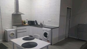 A compact kitchen with a built-in washing machine, a stove, and a microwave. - Palacio Congresos - Airport (Sevilla)
