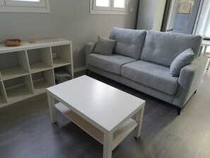 Un salon moderne avec un canapé gris, une table basse blanche et une étagère blanche.