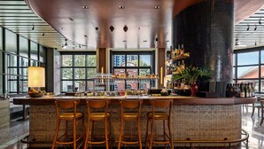A bar area with a high counter, four stools, and a large window. - Skyline 2-bed Near Crown With Pool and Sauna (Melbourne)