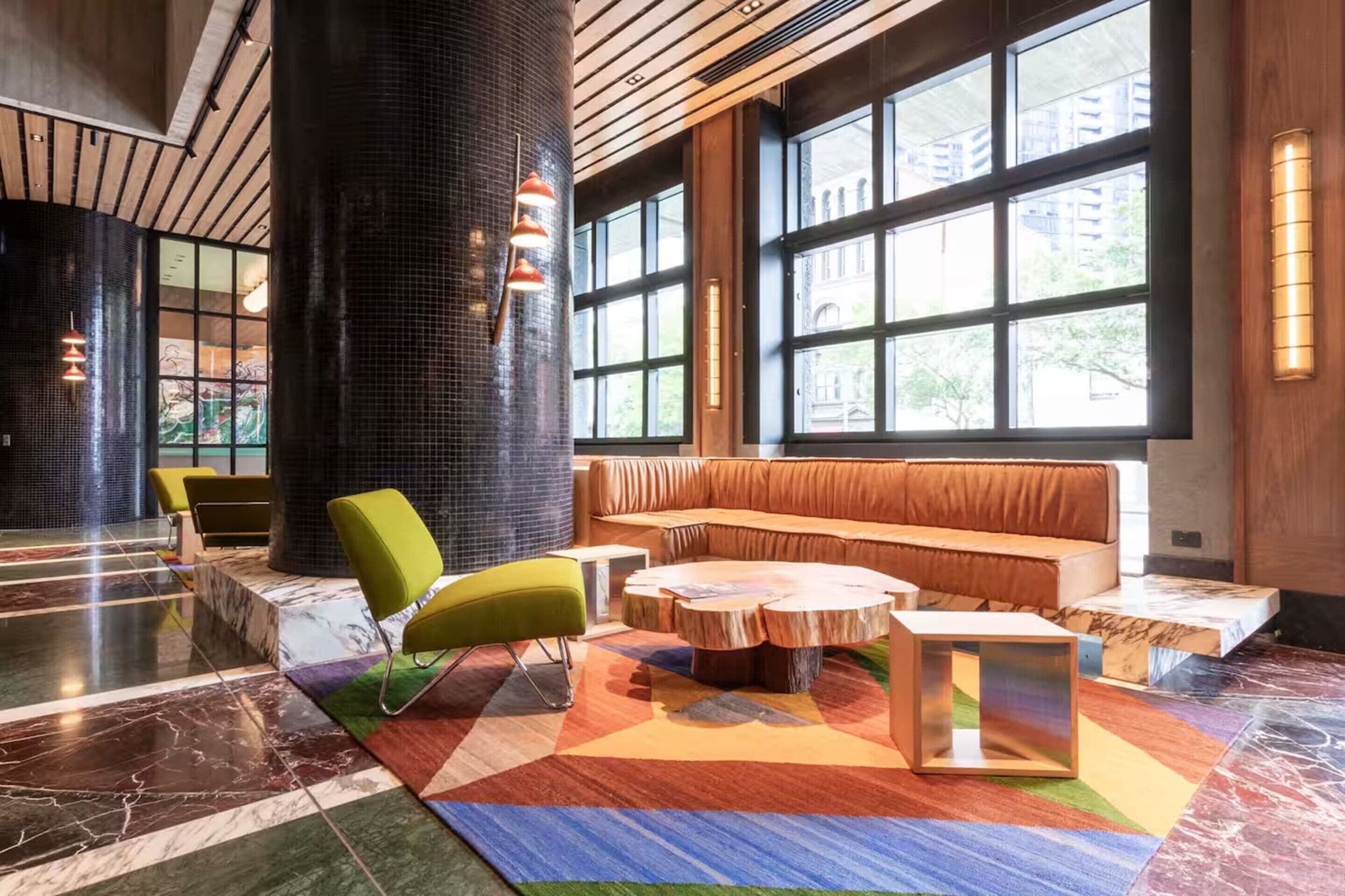 A lobby with a large column, a sofa, a round coffee table, and a patterned rug.