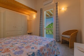Ein Schlafzimmer mit einem Bett, einem Korbstuhl, einem Kleiderschrank und einer Tür, die auf einen Balkon führt.