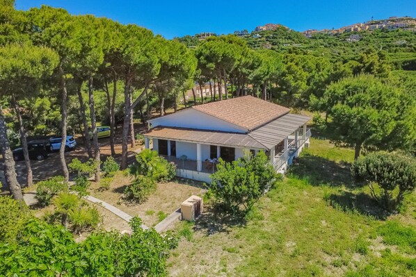 A single-story house with a tiled roof, surrounded by trees, and a clear view of the hillside in the background. - Villa Artistica - Villa Artistica - Rosso (Capoliveri)