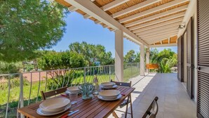 A covered outdoor dining area with a table set for four, surrounded by greenery and a clear view of the landscape. - Villa Artistica - Villa Artistica - Rosso (Capoliveri)