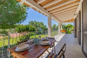 A covered outdoor dining area with a table set for four, surrounded by greenery and a clear view of the landscape. - Villa Artistica - Villa Artistica - Rosso (Capoliveri)
