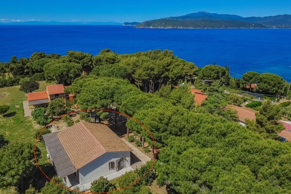 A residential area with houses surrounded by trees, a clear blue sea, and a mountainous backdrop. - Villa Artistica - Villa Artistica - Rosso (Capoliveri)