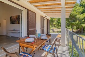 Un área de comedor al aire libre con una mesa de madera, sillas y vistas a árboles.