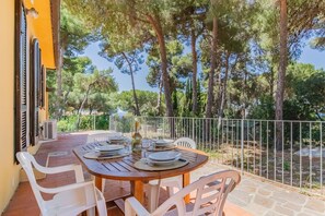 An outdoor patio with a table set for dining, surrounded by trees and a view of the sea. - Villa Valentina - Villa Valentina 2 (Capoliveri)