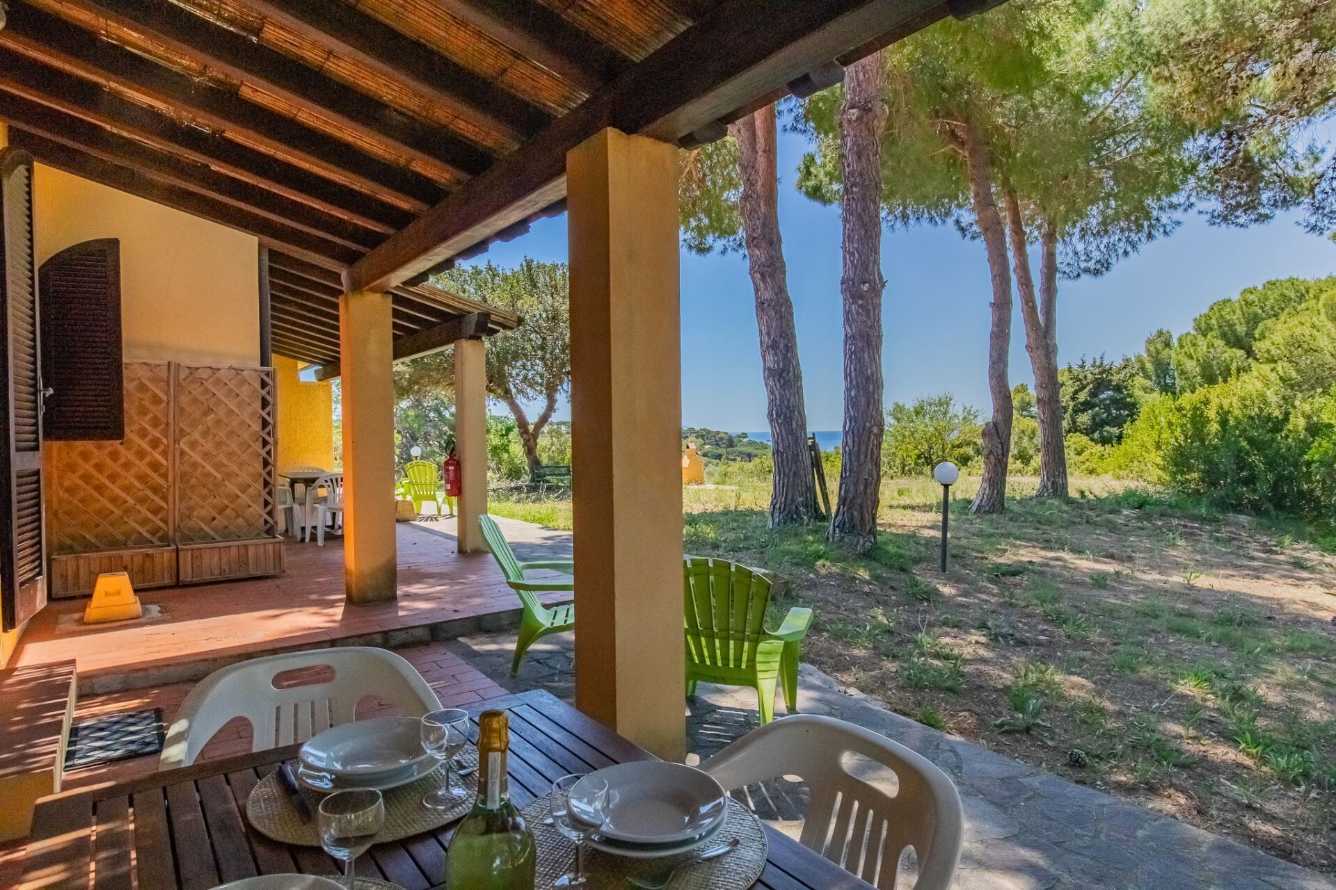 An outdoor dining area with a table set for two, chairs, and a view of the surrounding landscape.