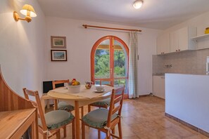 A dining area with a round table, wooden chairs, and a view through an arched window. - Villa Valentina - Villa Valentina 4 (Capoliveri)