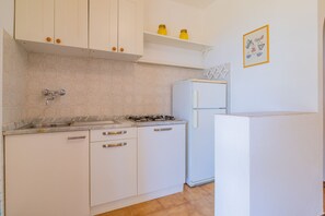 A kitchen with white cabinets, a sink, a stove, and a refrigerator. - Villa Valentina - Villa Valentina 4 (Capoliveri)