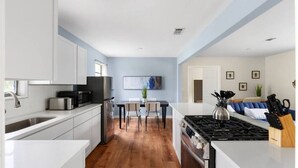 A modern kitchen with white cabinets, a dining area with a table and chairs, and a living area with a sofa and a coffee table. - Austin Backyard Retreat w/ Pool (Austin)