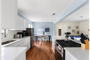 A modern kitchen with white cabinets, a dining area with a table and chairs, and a living area with a sofa and a coffee table. - Austin Backyard Retreat w/ Pool (Austin)