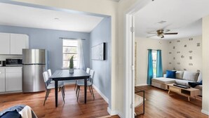 A modern kitchen with a built-in refrigerator, a dining area with a table and chairs, and a living space with a sofa and a ceiling fan. - Austin Backyard Retreat w/ Pool (Austin)