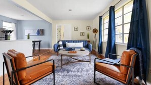 A modern living room with a blue sofa, two leather armchairs, a coffee table, and a floor lamp. - Austin Backyard Retreat w/ Pool (Austin)