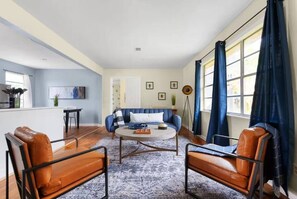 A modern living room with a blue sofa, two leather armchairs, a coffee table, and a floor lamp. - Austin Backyard Retreat w/ Pool (Austin)