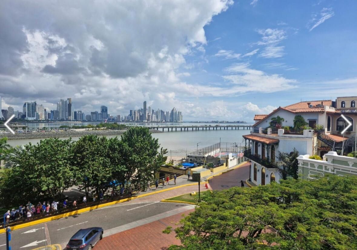 A coastal cityscape with a prominent bridge, a marina, and a mix of modern and traditional architecture.