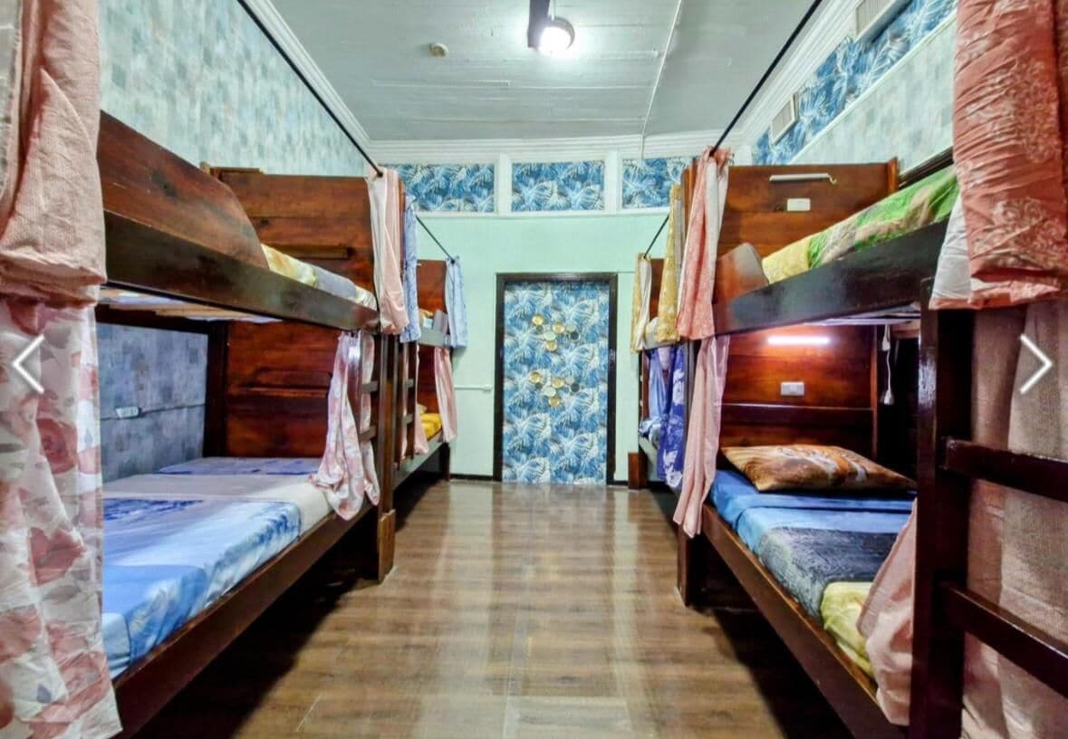 Ein Schlafsaalzimmer mit Etagenbetten, Fliesenboden und einer Tür mit floralem Dekor.