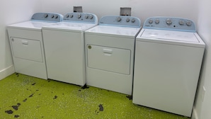 A row of four Whirlpool washers in a laundry room with green speckled flooring. - Modern Suite Near Hot Springs & Ouachita River (Malvern)