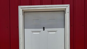 A white door with a numeric keypad, set in a red building. - Modern Suite Near Hot Springs & Ouachita River (Malvern)