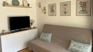 A living room with a TV, sofa, and decorative pillows. - Nauticap cap d'agde (Agde)