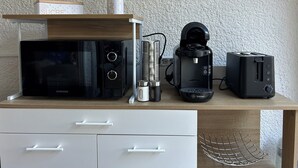 A kitchen with a microwave, coffee maker, and toaster on a wooden countertop. - Nauticap cap d'agde (Agde)