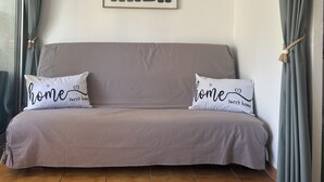 A beige sofa with two pillows, a framed abstract artwork, and a curtain. - Nauticap cap d'agde (Agde)