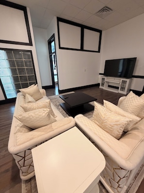 A living room with a sofa, a coffee table, and a TV on a stand.