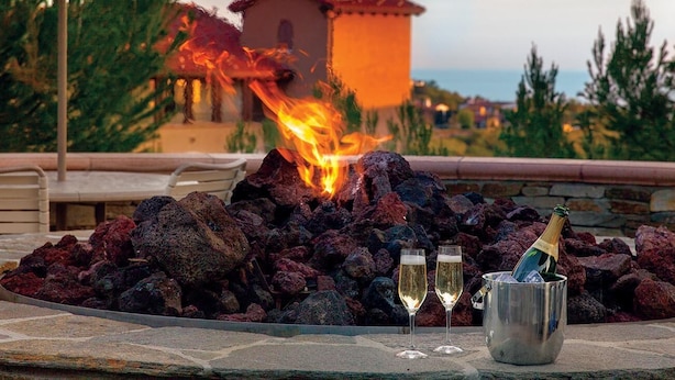 A fire pit with rocks, two champagne glasses, and a bottle. - 2-bedroom resort in gorgeous Newport Beach with fitness room and AC (Newport Beach)