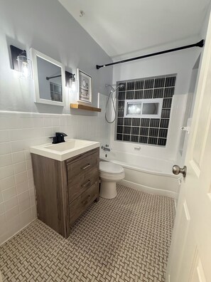 A bathroom with a white vanity, a toilet, a bathtub, and a shower. - Charming 3-bedroom house in wonderful St. Louis with AC (St. Louis)