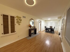 A hallway with a dining area, wooden floors, a console table with a vase of flowers, and a mirror. - Charming 3-bedroom house in wonderful St. Louis with AC (St. Louis)