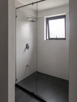 Une douche moderne avec une porte en verre, une fenêtre et un sol carrelé.