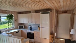 A compact kitchen with wooden cabinets, a microwave, a stove, and a refrigerator.