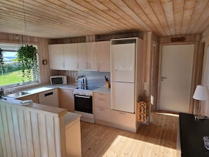 Una cocina compacta con armarios de madera, microondas, estufa y refrigerador.