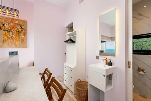 Ein modernes Badezimmer mit großem Spiegel, Waschbecken und Duschbereich.