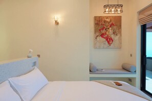 Ein Schlafzimmer mit einem Bett, einer Wandleuchte, einem Gemälde, einem Fenster und einem Balkon.