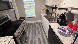 A compact kitchen with a stove, oven, microwave, and sink. - Charming 3-bedroom house in brilliant Fort Worth with AC (Fort Worth)