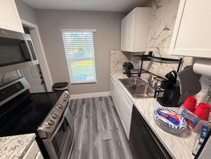 A compact kitchen with a stove, oven, microwave, and sink. - Charming 3-bedroom house in brilliant Fort Worth with AC (Fort Worth)