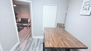 A dining room with a wooden table and chairs, a window with blinds, and a sign on the wall. - Charming 3-bedroom house in brilliant Fort Worth with AC (Fort Worth)