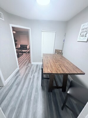 A dining room with a wooden table and chairs, a window with blinds, and a sign on the wall. - Charming 3-bedroom house in brilliant Fort Worth with AC (Fort Worth)