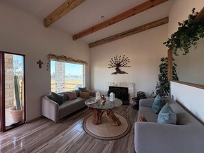 Una sala de estar con chimenea, un sofá, una mesa de centro y un cactus.