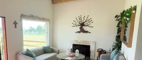 A spacious living room with a fireplace, two sofas, a coffee table, and wooden beams on the ceiling.