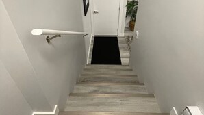 Eine Treppe mit einer schwarzen Matte am unteren Ende, weißen Wänden und einer Tür am oberen Ende.