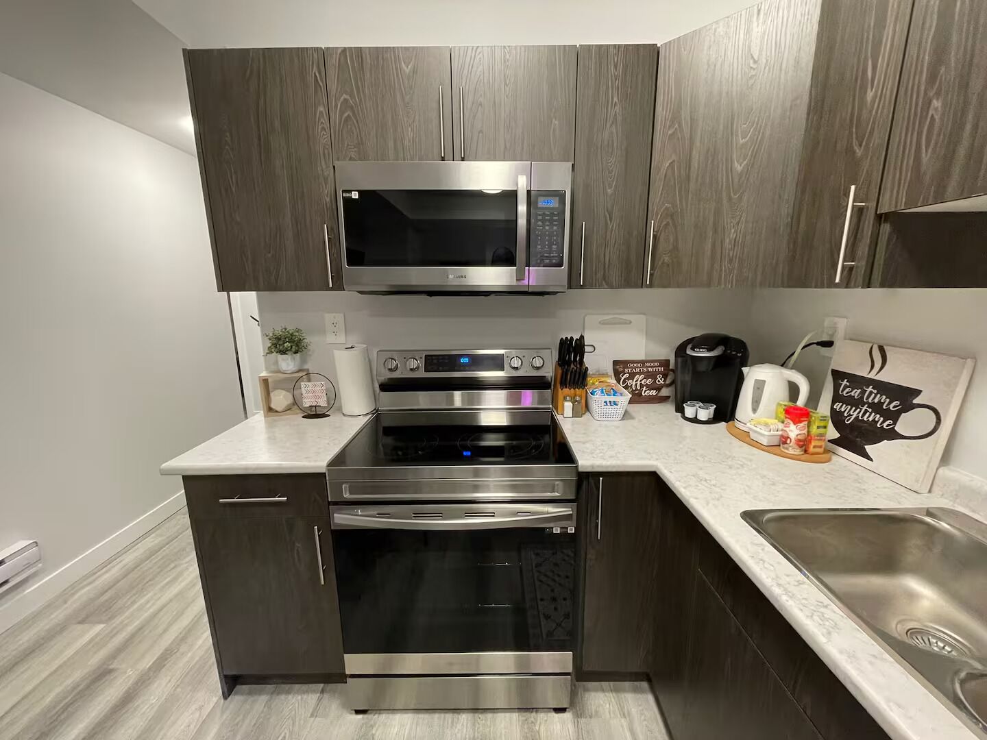 A modern kitchen with a microwave, oven, and sink.