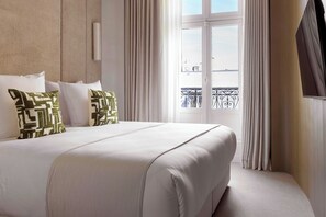 A hotel room with a large bed, white bedding, and a view of the city through the window. - Luxury Flat -2br/6p- Madeleine/saint Honore (Paris)