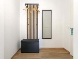 A hallway with a black bench, a vertical wooden slat panel, and a mirror on the wall. - Stylish apartment in the centre of Jenbach (Jenbach)
