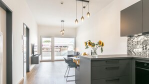 Eine moderne Küche mit einer zentralen Kochinsel, dunklen Schränken und Blick auf einen Balkon.