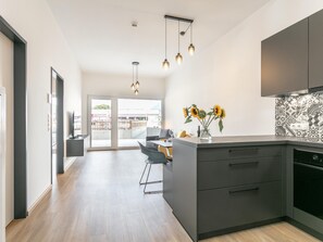 A modern kitchen with a central island, dark cabinetry, and a view to an outdoor balcony. - Modern holiday apartment with terrace in Jenbach (Jenbach)