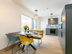 A modern kitchen with a dining area, featuring a table with chairs, a vase with flowers, and a bottle. - Modern holiday apartment with terrace in Jenbach (Jenbach)