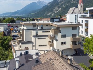 A multi-story residential building with balconies, a parking area, and a view of mountains in the background. - Modern holiday apartment with terrace in Jenbach (Jenbach)
